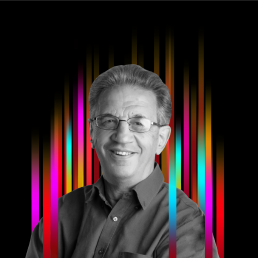 On the middle of a black background is a row of colourful vertical stripes’. In the centre is a black and white profile photo of TEDx speaker Sir Julian Le Grand superimposed on top.
